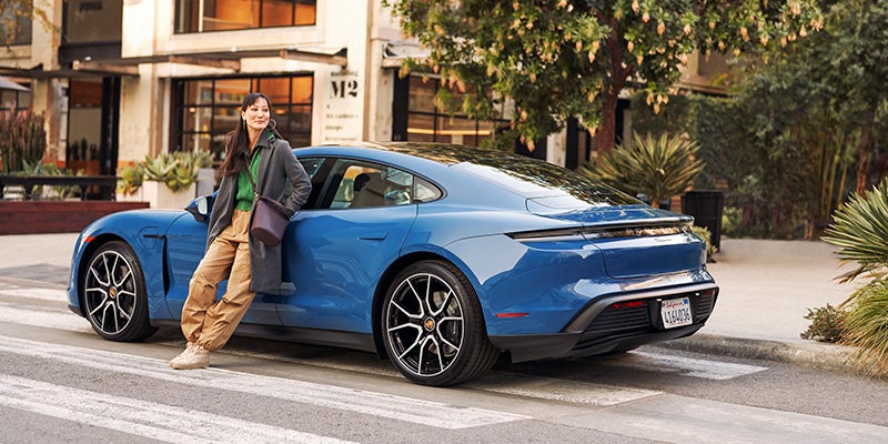 woman leaning against her brand new Porsche Taycan